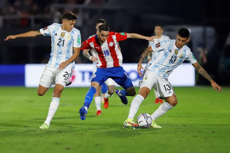 Miguel Almirón de Paraguay disputa el balón con Cristian Romero (d) y Nahuel Molina (i) de Argentina, durante un partido por las eliminatorias sudamericanas para el Mundial de Catar 2022, en el estadio Defensores del Chaco en Asunción (Paraguay).