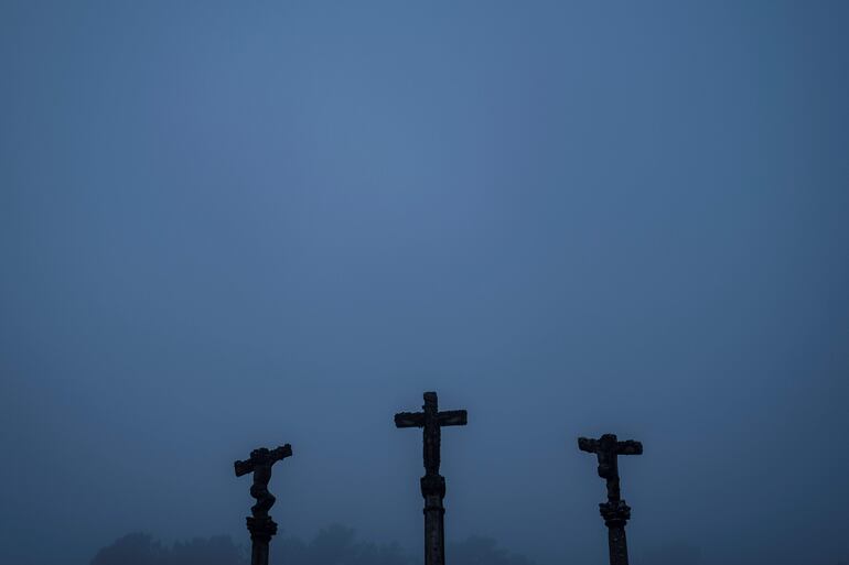 Detalle de tres cruceiros en el entorno de la iglesia de Beade, en la comarca orensana de O Ribeiro bajo una manta de niebla.