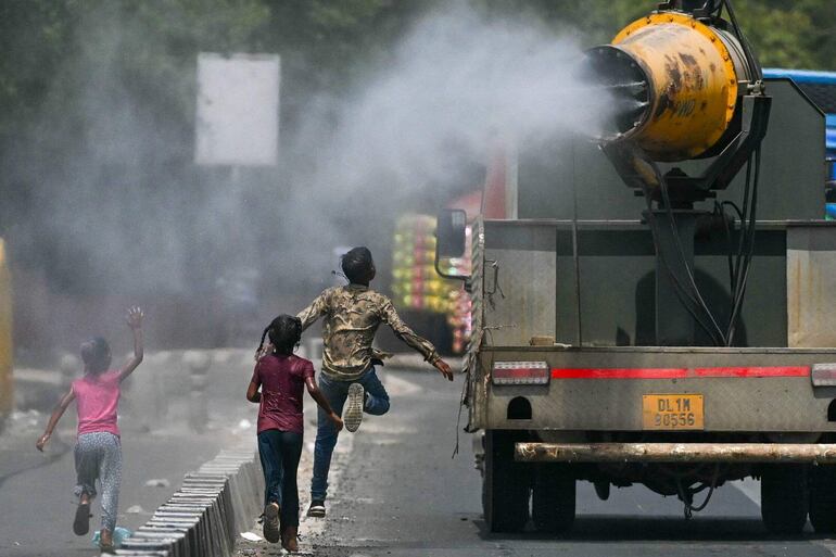 Niños corren detrás de un camión que rocía agua, el martes en Nueva Delhi, India.