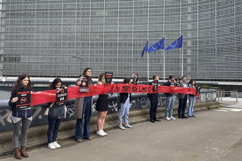 Representantes de organizaciones humanitarias colocaron este lunes una cinta roja frente a las instituciones comunitarias en Bruselas, donde se celebra hoy el Consejo de ministros de Exteriores de la Unión Europea.