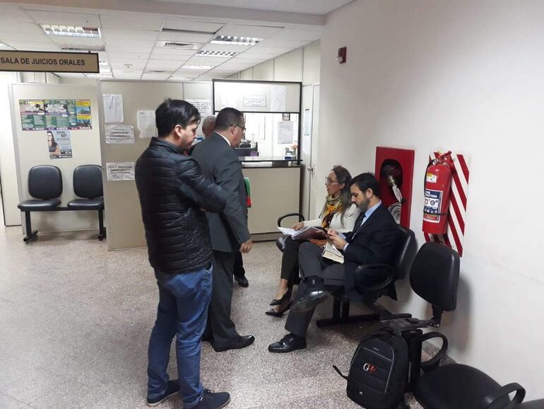 Los abogados  esperan  el inicio de la audiencia, en la pasillo del Palacio de Justicia de San Lorenzo.