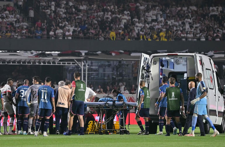 El defensor de Nacional, Juan Manuel Izquierdo (cubierto), recibe atención médica después de desmayarse durante el partido de vuelta de los octavos de final de la Copa Libertadores entre el Sao Paulo de Brasil y el Nacional de Uruguay en el estadio Morumbí de Sao Paulo.