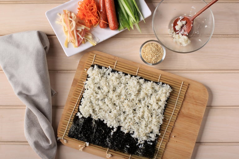 El arroz para sushi sobre las hojas de alga nori.