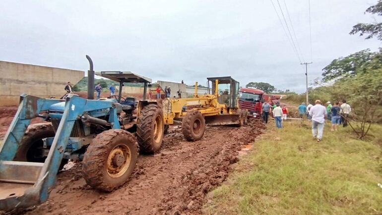 Un tractor y una motoniveladora se preparan para estirar un camión semirremolque que se quedó empantanado en la ruta que une el centro urbano de Abaí con la compañía Tuna.