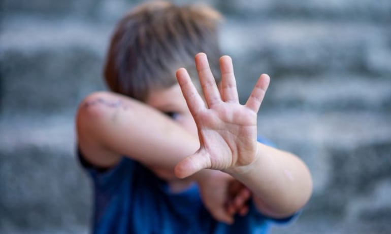 imagen figurativa de niño evitando un golpe con la palma de su mano