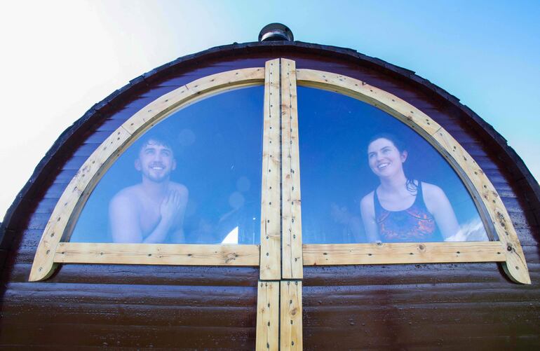 La gente mira desde el interior de un sauna en la playa de Baginbun, cerca de Wexford, en la costa sureste de Irlanda.