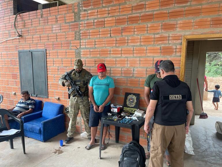 El policía retirado Reinaldo Ortiz, de remera celeste, y el supuesto miembro del PCC, Carlos Benítez, de remera verde, posan junto a las evidencias.