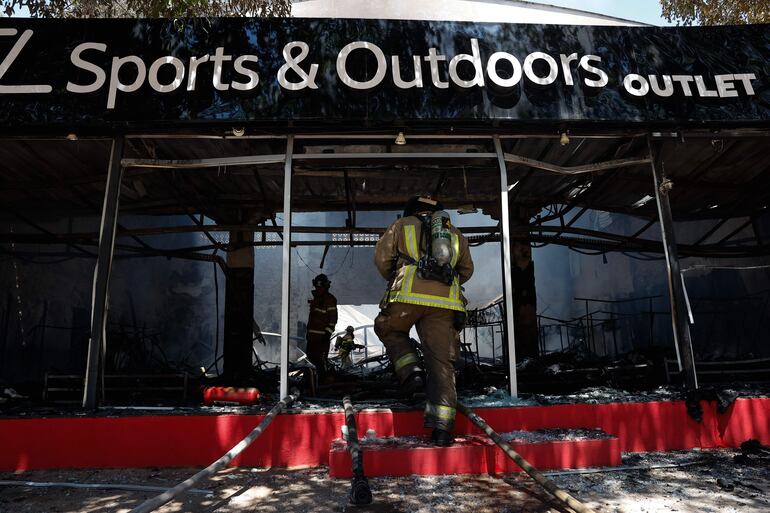 Bomberos voluntarios controlan un incendio de gran magnitud en un depósito de ropa deportiva.