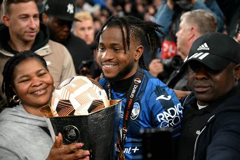 Atalanta's Nigerian forward #11 Ademola Lookman with his family, poses with the match ball for scoring a hat-trick, and the trophy after the UEFA Europa League final football match between Atalanta and Bayer Leverkusen at the Dublin Arena stadium, in Dublin, on May 22, 2024. Lookman scored all three goals as Atalanta won the game 3-0. (Photo by Paul ELLIS / AFP)