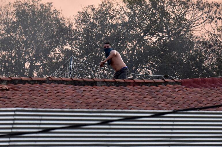 Un interno tira piedras desde el tejado de Tacumbú, luego de que la Penitenciaría fuera tomada por los presos.