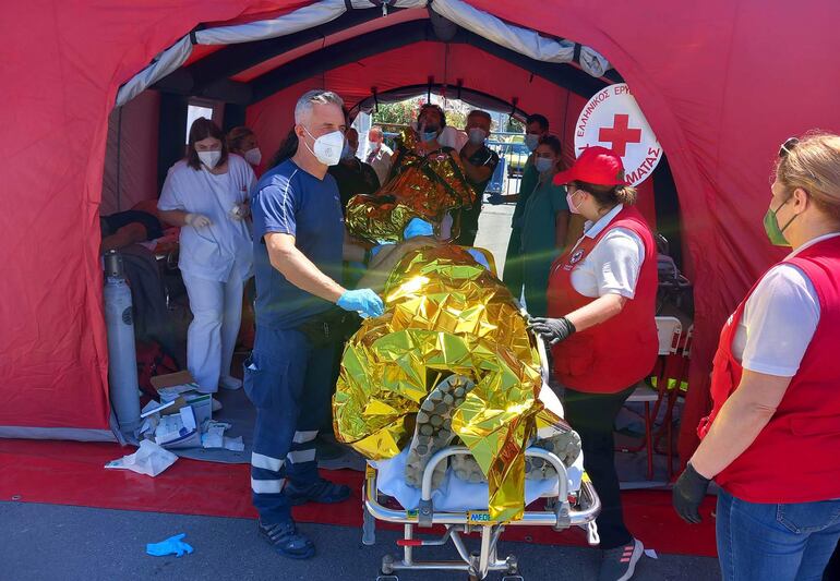 Paramédicos del Servicio Nacional de Ambulancias de Emergencia de Grecia (EKAV) y miembros de la Cruz Roja griega ayudan a migrantes supervivientes del hundimiento de un pesquero en su llegada en el puerto de Kalamata este miércoles.