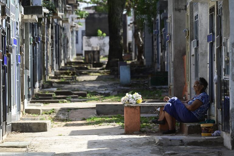 Señora descansa frente al panteón familiar en el Cementerio del Sur.