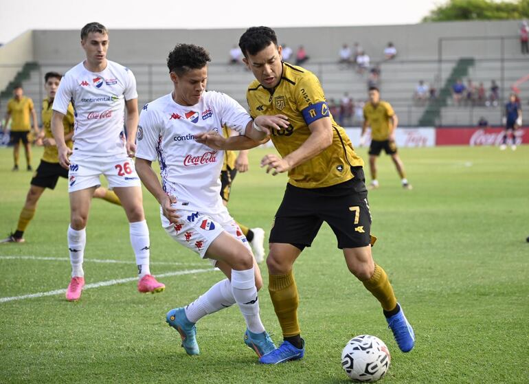 Néstor Camacho (d), futbolista de Guaraní, pelea por el balón con Carlos Espínola, jugador de Nacional, en un partido por el fútbol paraguayo.