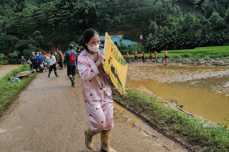 Una residente lleva una fotografía de un retrato de boda en el lugar de un deslizamiento de tierra en la remota aldea montañosa de Lang Nu, en la provincia de Lao Cai, el 12 de septiembre de 2024, después de que el tifón Yagi azotó el norte de Vietnam.