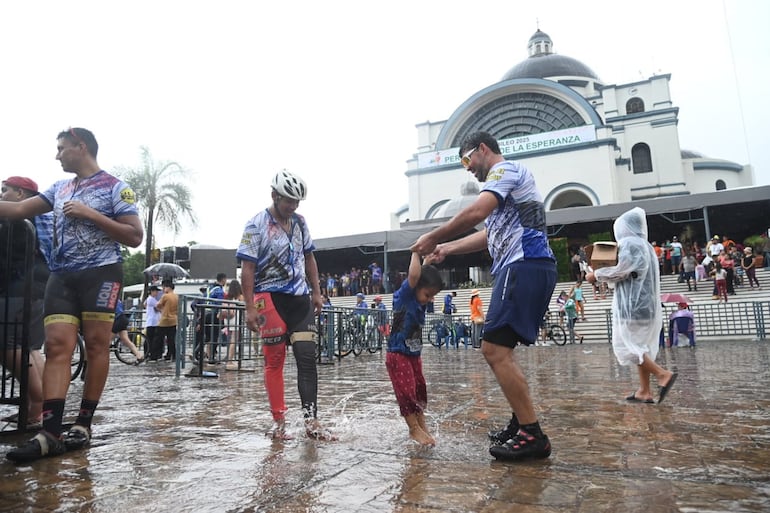 Ciclistas juegan con un niño ante la lluvia que cae en la Villa Serrana.