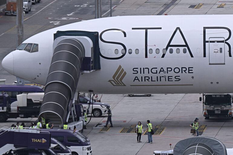 Oficiales se reúnen alrededor del avión de Singapore Airlines, un Boeing 777-300ER, estacionado en el aeropuerto internacional Suvarnabhumi en Bangkok.