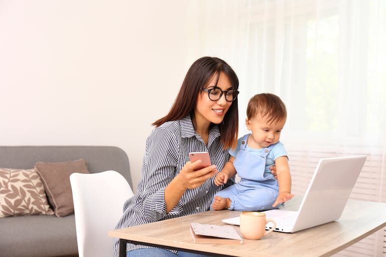 Una mujer realiza teletrabajo desde su casa, con su bebé.