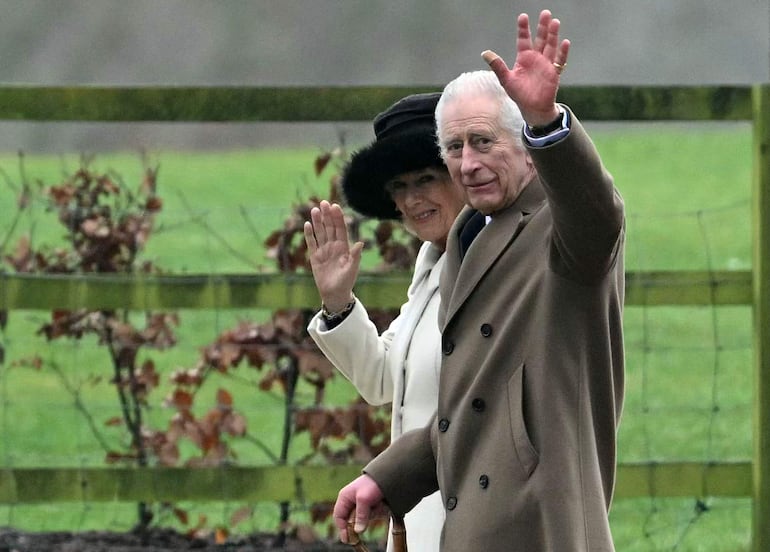 El rey Carlos III de Gran Bretaña y la reina Camilla de Gran Bretaña saludan al salir después de asistir a un servicio en la iglesia de Santa María Magdalena en Sandringham Estate, en el este de Inglaterra, el 11 de febrero de 2024.