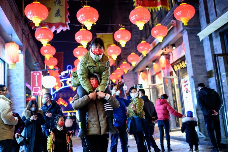 Personas con mascarillas caminan por la calle Qianmen en Beijing el 11 de febrero de 2021, antes del Año Nuevo Lunar, que marca el comienzo del Año del Buey el 12 de febrero.