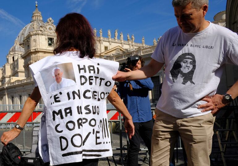 Una mujer viste una camiseta con una foto del Papa y dice "Dijo que estaba en el cielo, pero ¿dónde está su cuerpo?" refiriéndose a Emanuela Orlandi, una adolescente que desapareció en 1983 en uno de los misterios más oscuros de Italia.