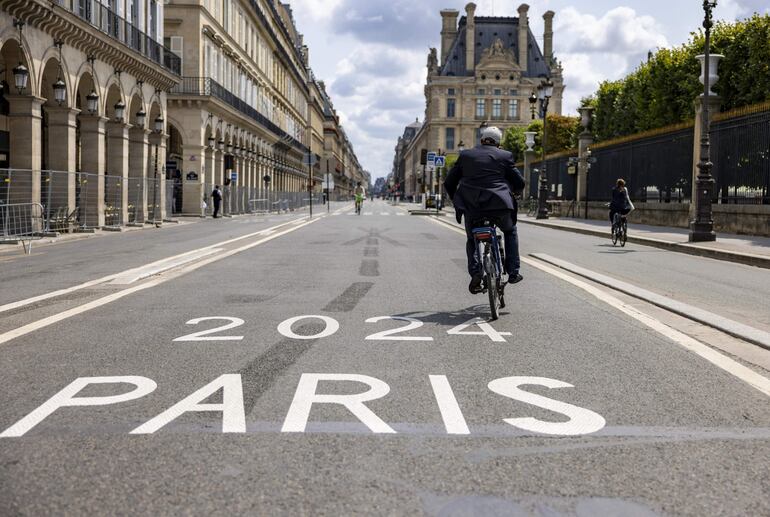 Un hombre en bicicleta pedalea su bicicleta por una calle vacía en París, Francia, donde hoy se inauguran oficialmente los Juegos Olímpicos París 2024. 