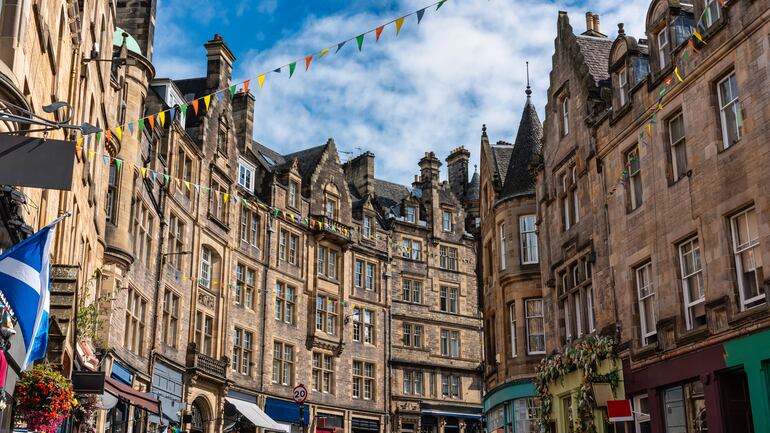 Calle comercial Cockburn con coloridas tiendas y viejos edificios de piedra en Edimburgo, Escocia.