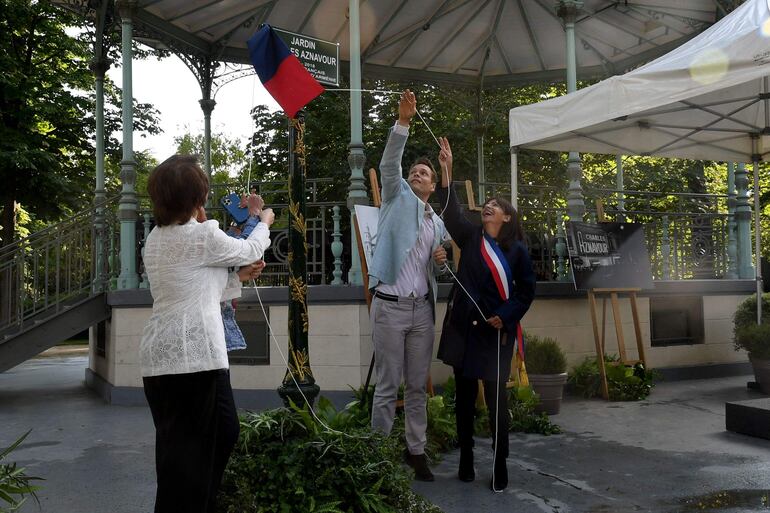 Nicolas Aznavour (centro) revela una placa con la alcaldesa de París, Anne Hidalgo (derecha), durante la inauguración de un jardín en la avenida de los Campos Elíseos que lleva el nombre de su padre, el cantante franco-armenio Charles Aznavour.