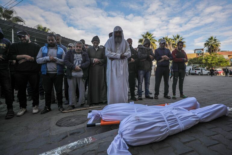 Un grupo de personas reza junto a los cuerpos de fallecidos en un bombardeo israelí en Deir el Balah, en la zona centro de la Franja de Gaza, este jueves.
