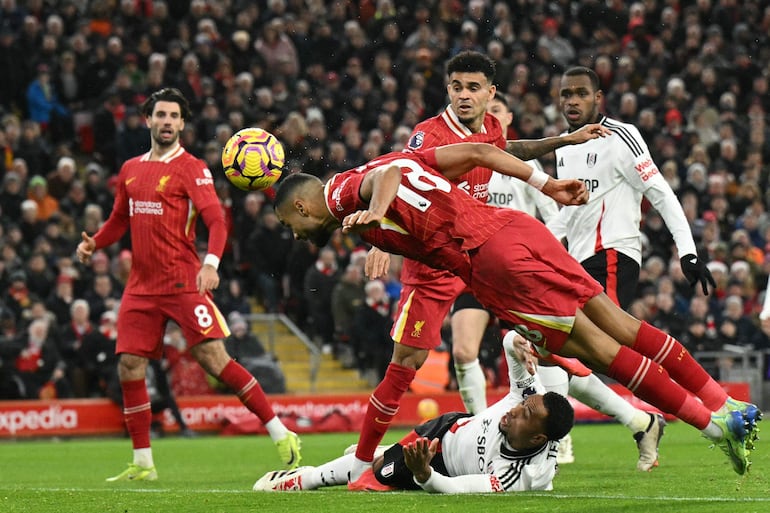 TOPSHOT - Liverpool's Dutch striker #18 Cody Gakpo heads home their first goal during the English Premier League football match between Liverpool and Fulham at Anfield in Liverpool, north west England on December 14, 2024. (Photo by Oli SCARFF / AFP) / RESTRICTED TO EDITORIAL USE. No use with unauthorized audio, video, data, fixture lists, club/league logos or 'live' services. Online in-match use limited to 120 images. An additional 40 images may be used in extra time. No video emulation. Social media in-match use limited to 120 images. An additional 40 images may be used in extra time. No use in betting publications, games or single club/league/player publications. / 