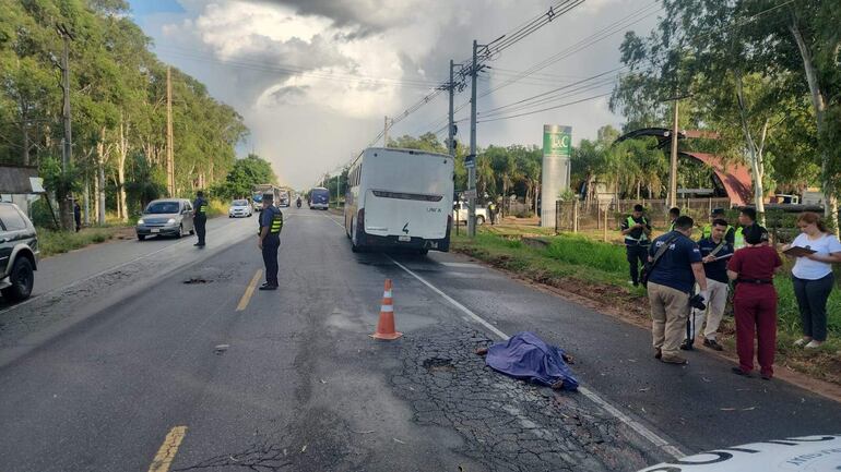 El cuerpo sin vida de la mujer, ya tapado con una sábana, tendido en el pavimento, y en el fondo el ómnibus de la línea 47 involucrado en el fatal percance.