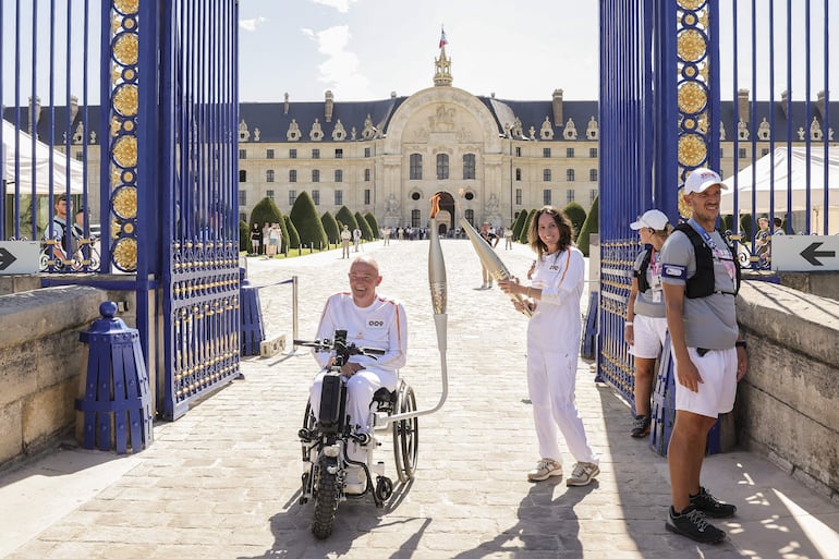 El atleta francés Damien Letulle (L) lleva la llama Paralímpica durante el relevo de la antorcha Paralímpica en los Inválidos de París, Francia, 28 de agosto de 2024.