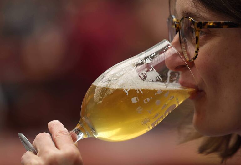 Una mujer bebe un copón de cerveza. 
