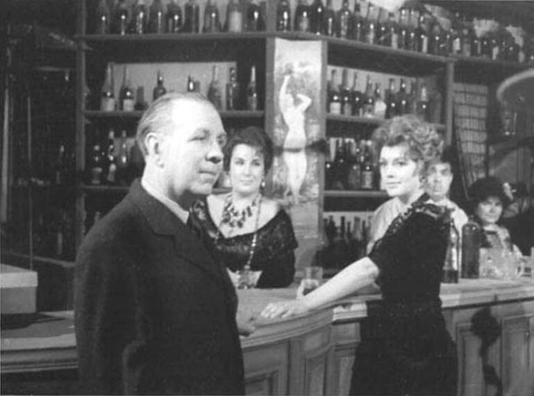 Jorge Luis Borges en 1962 en una visita al set durante la filmación de "Hombre de la esquina rosada". En la barra, las actrices Susana Campos y Berta Ortigosa. (Museo del Cine Pablo C. Ducrós Hicken).