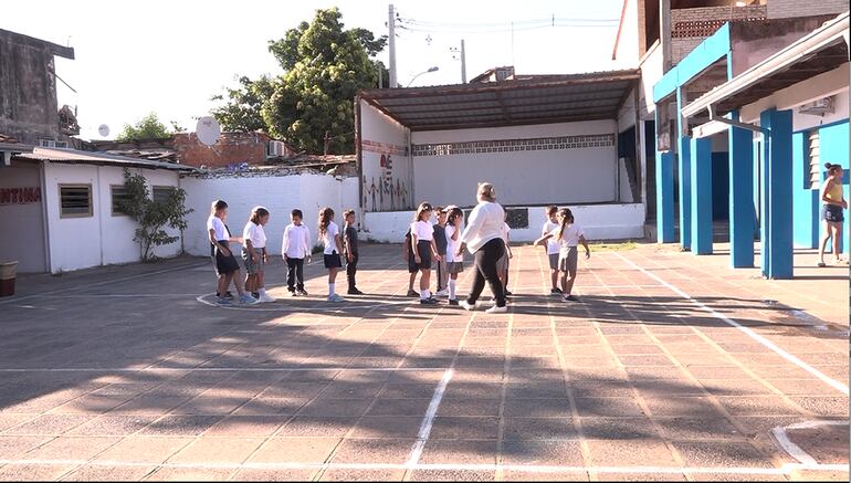 Niños juegan en el patio de una institución bajo el sol. 