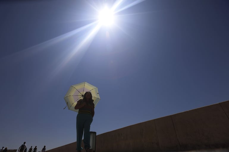 Imagen ilustrativa: una mujer se protege del sol con una sombrilla.
