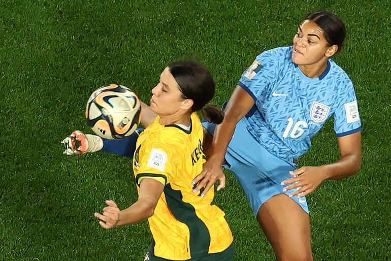 La británica Jessica Carter (d) intenta puntear la pelota, que la australiana Sam Kerr quiere dominarla con el pecho.