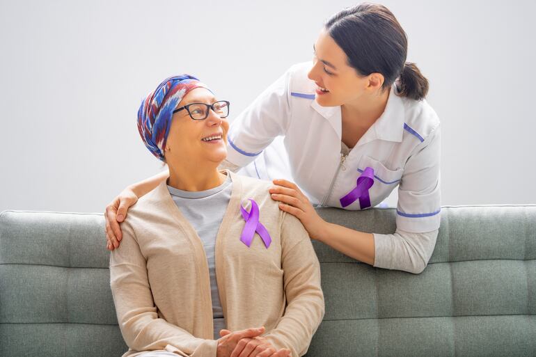 Paciente y personal médico con lazo de color fucsia en el Día Mundial contra el Cáncer.