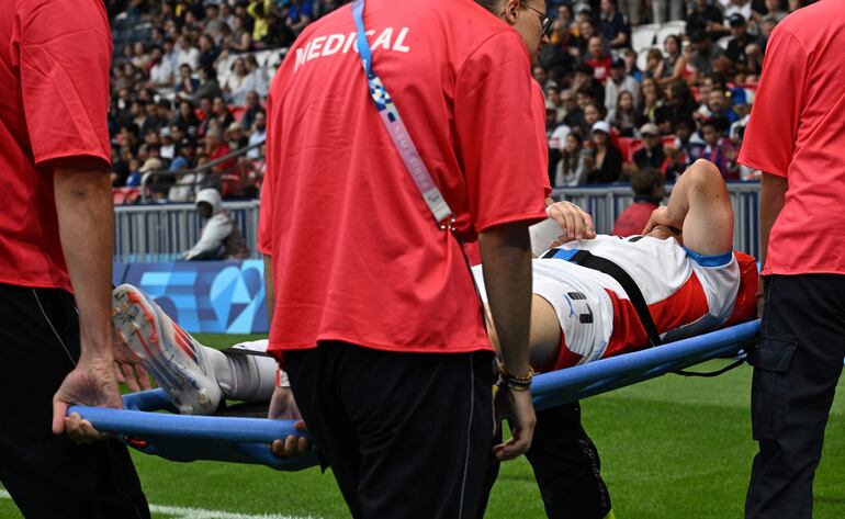 Enso González, jugador de la selección de Paraguay, deja el campo de juego en camilla a causa de una lesión en la rodilla derecha durante el partido frente a Israel por la segunda fecha del Grupo D del Torneo de Fútbol masculino de los Juegos Olímpicos París 2024 en el estadio Parque de los Príncipes, en París, Francia.