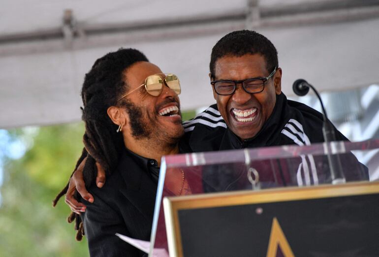 Lenny Kravitz y su gran amigo, el actor Denzel Washington dándose un abrazo. (VALERIE MACON / AFP)