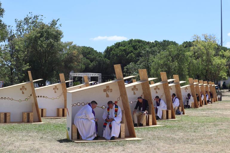 Varias personas se confiesan en unos de los 150 confesionarios, construidos por reclusos portugueses, que ofrecerán este sacramento a los fieles en el Parque del Perdón, por la JMJ.
