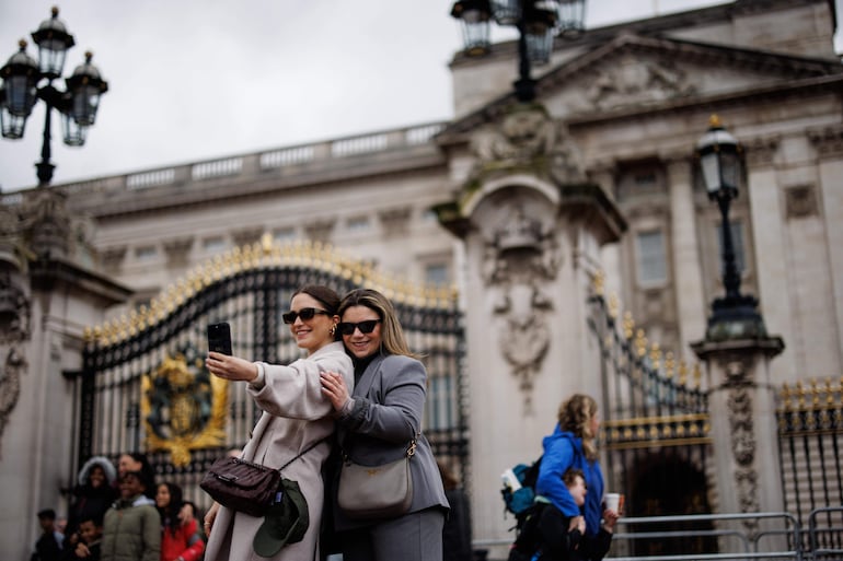 Imagen ilustrativa: jóvenes se sacan fotos frente al Palacio de Buckingham en Londres.