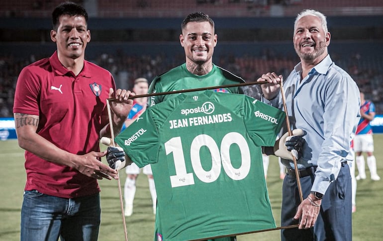 Julio dos Santos y el presidente Juan José Zapag hacen entrega del reconocimiento a Jean Fernandes por sus 100 partidos con el Ciclón.