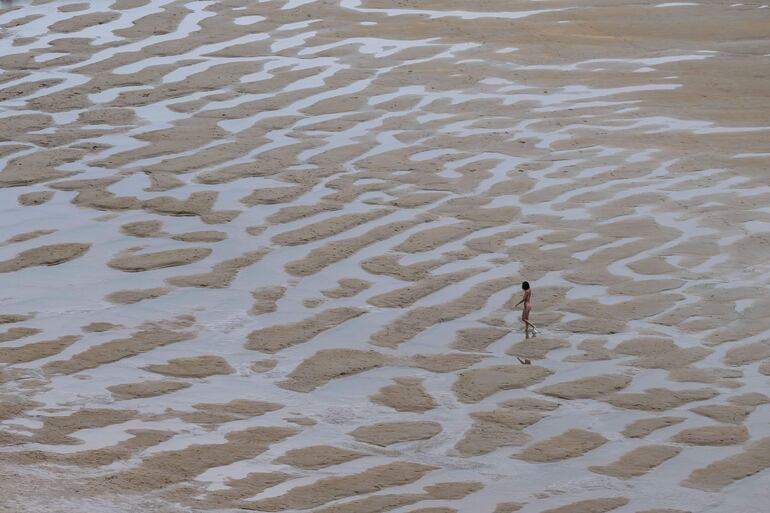 Una mujer camina por la playa de Los Locos este viernes en la localidad cántabra de Suances.