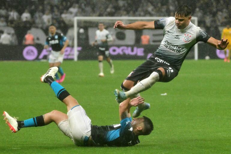 Corinthians' Paraguayan forward #11 Angel Romero (Top) and Racing's defender #27 Gabriel Rojas fight for the ball during the Copa Sudamericana semi-final first leg football match between Brazil's Corinthians and Argentina's Racing at the Neo Quimica Arena stadium in Sao Paulo, Brazil, on October 24, 2024. (Photo by NELSON ALMEIDA / AFP)