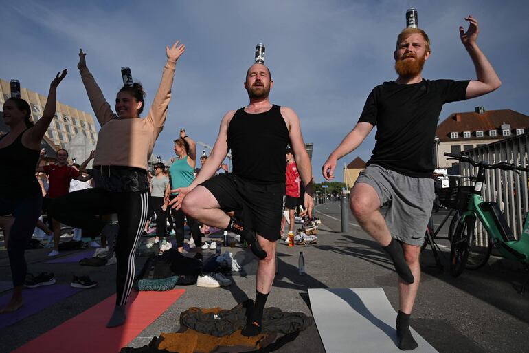 Participantes del evento "Cerveza y yoga" hacen la postura del árbol o vrikshasana, en Copenhague, Dinamarca. 