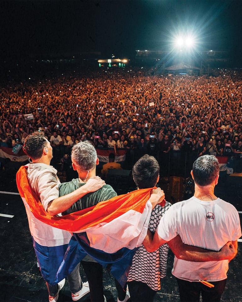 Los integrantes de Keane abrazados con la bandera paraguaya y ante la multitudinaria concurrencia del Kilkfest en Asunción.