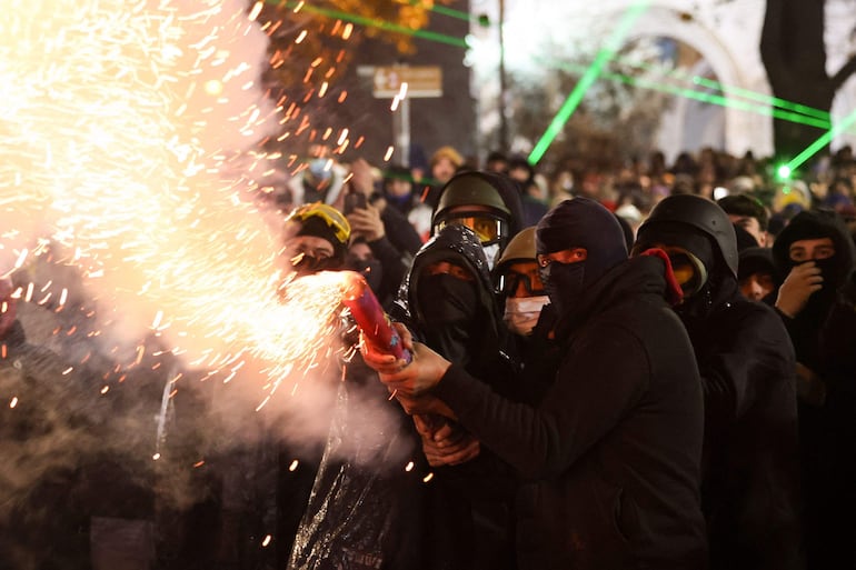 Manifestantes lanzan pirotecnia hacia la policía este lunes en Tiflis, durante el cuarto día de protestas en Georgia.