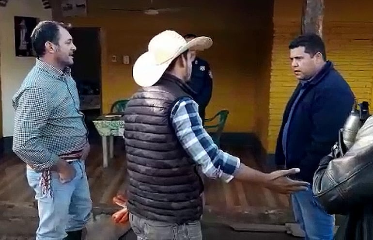 El gobernador del departamento de San Pedro, Carlos Giménez (izq.) y su hijo (de sombrero) increpan al periodista Adán Rojas Martínez (der.), quien investigaba el uso de las maquinarias.