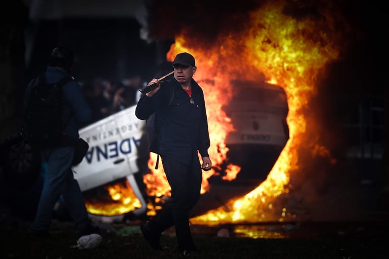 Un hombre es visto caminar frente a una carro en llamas en una protesta a las afueras del senado durante un debate este miércoles, en Buenos Aires (Argentina).