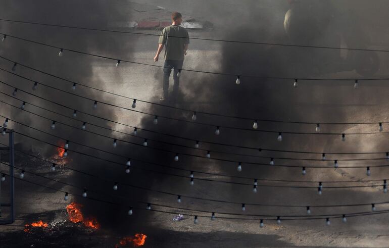 Un hombre palestino camina junto a escombros en llamas, el martes en Yenín, Cisjordania.